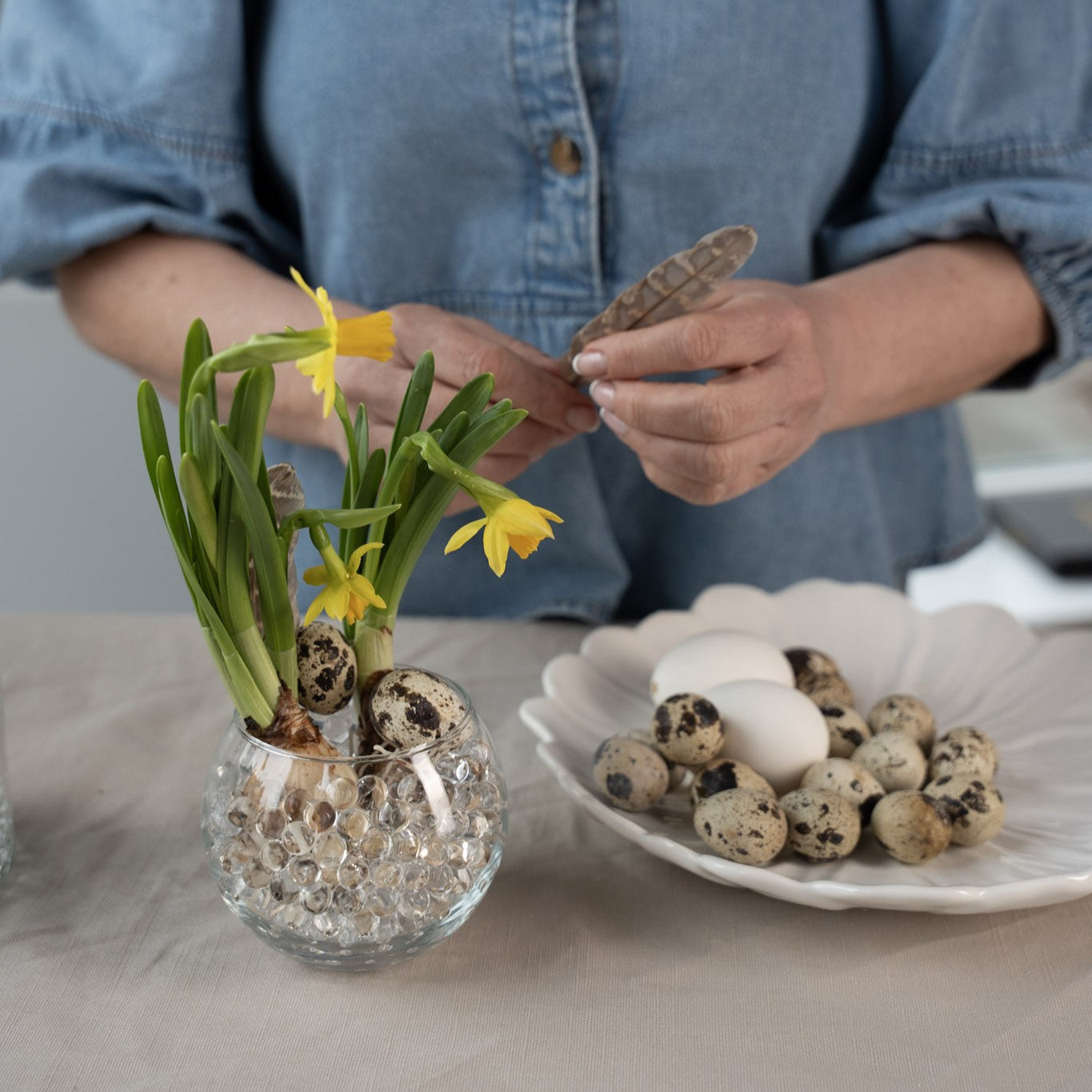 Person arranging flowers in a vase with hanataba waterbubbles and quail eggs on a table