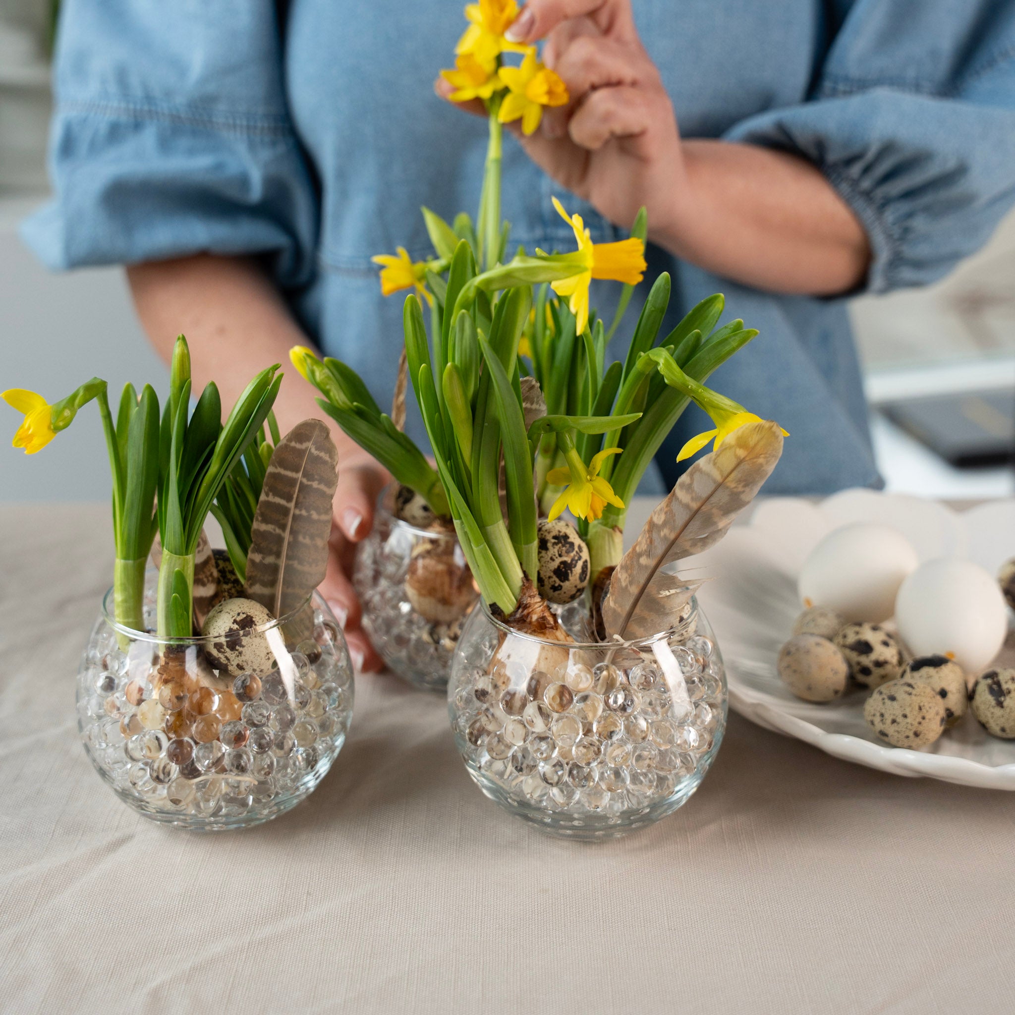 Three small glass vases with yellow flowers and decorative hanataba waterbubbles, standing on a table.