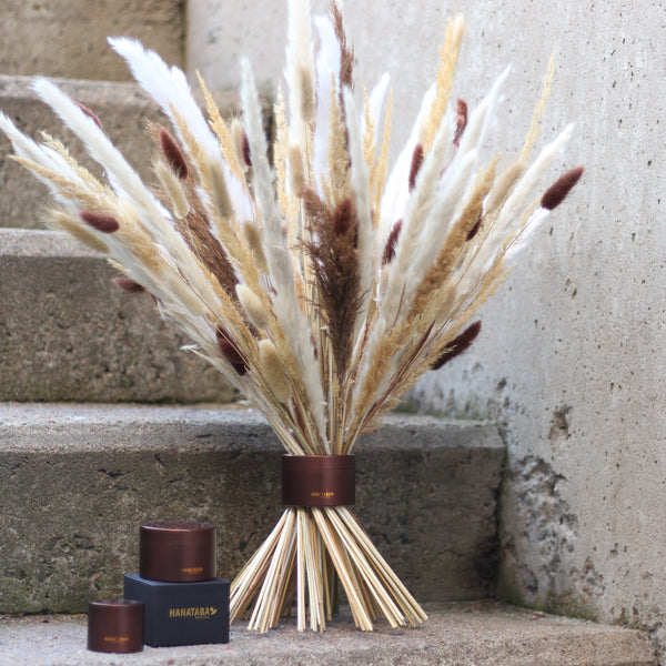 A Muddy Brown Hanataba bouquet twister elegantly supports an arrangement of dried grasses and reeds on concrete steps, accompanied by two matching Hanataba containers.
