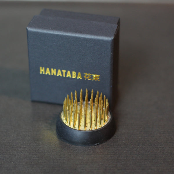 A 34mm Kenzan ring from Hanataba with golden spikes, displayed beside its dark blue box with gold lettering.